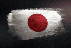 Red disc of the Japanese flag painted on a rough white brushstroke against a dark textured background.