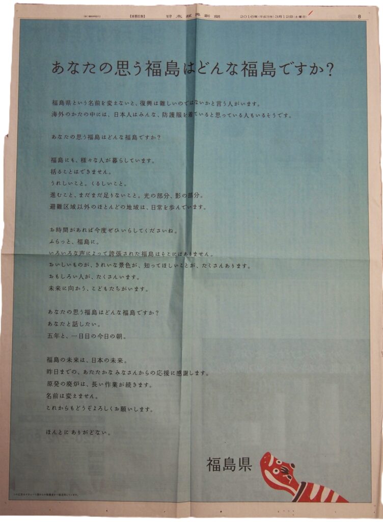 Japanese newspaper spread with a blue-tinted background and a large headline asking, “What kind of Fukushima is yours?” followed by column text and a red cartoon figure at the bottom-right corner.