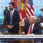 In the Oval Office, a man in a dark suit stands beside a seated man in a suit with a red tie; behind them are US flags, a large desk, and framed photos, with a news ticker at the bottom saying “TEXT POTUS TO 45470 FOR UPDATES FROM THE WHITE HOUSE.”