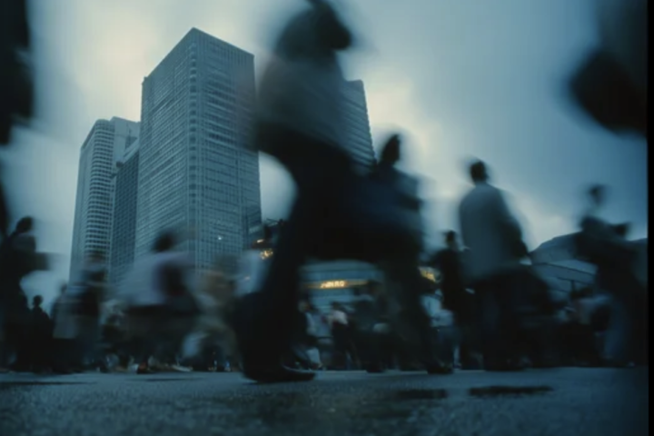 Blurred pedestrians move through a busy city plaza with tall skyscrapers in the background, conveying urban bustle.